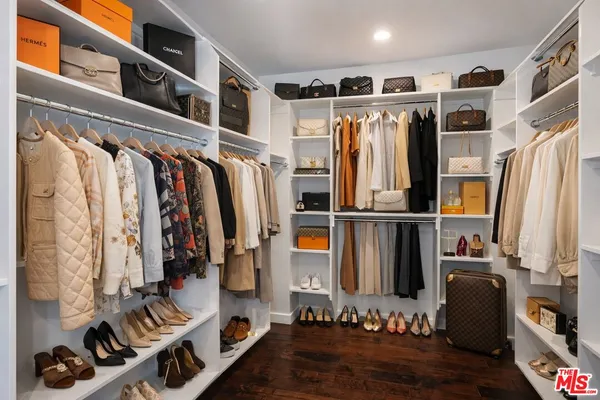 a view of walk in closet with clothes and shoes