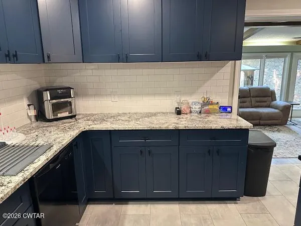 a kitchen with granite countertop a sink dishwasher stove and cabinets