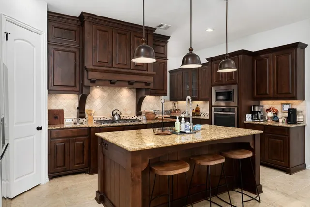 a kitchen with kitchen island granite countertop a sink stove and cabinets