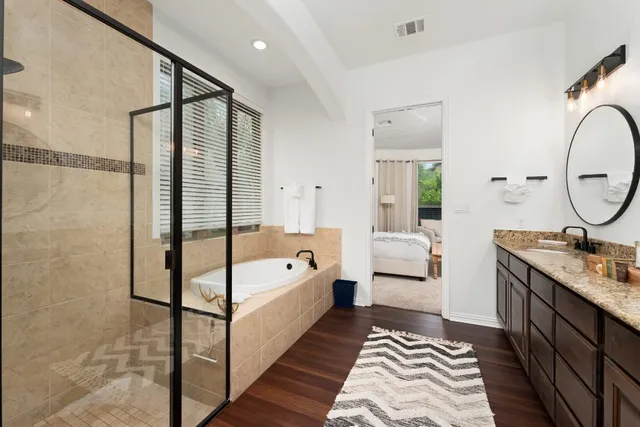 a en suite spacious bathroom with a double vanity sink a mirror and a bathtub