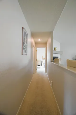 a view of a hallway with wooden floor and a bathroom
