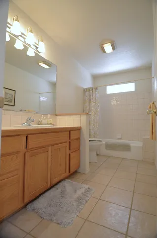 a spacious bathroom with a granite countertop sink a toilet and a mirror