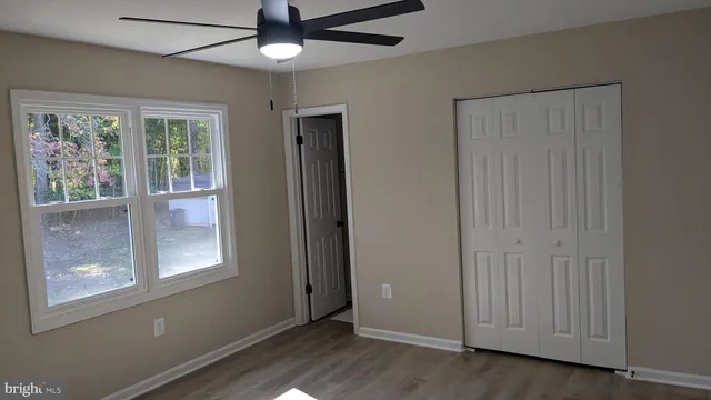a view of an empty room with a window and wooden floor