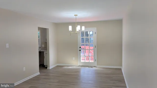 an empty room with wooden floor chandelier and windows