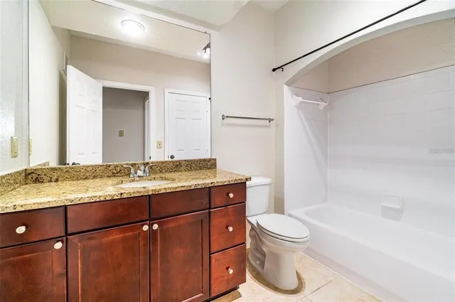 a bathroom with a granite countertop sink toilet a mirror and bathtub