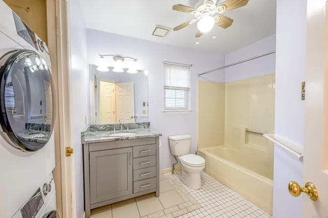 a bathroom with a granite countertop toilet a sink a mirror a bathtub and shower