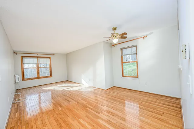 a view of an empty room with a window and wooden floor