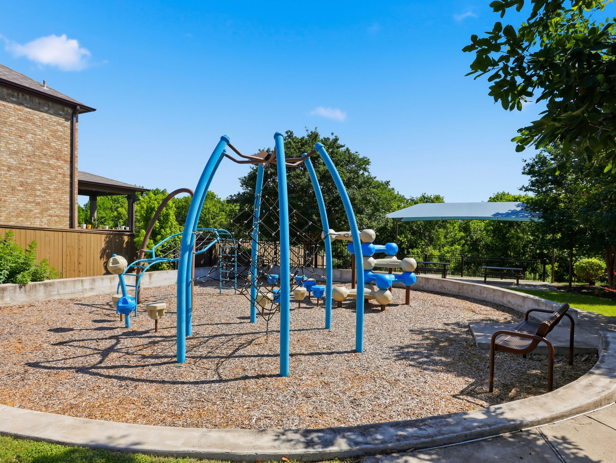 640 Landon Samuel Loop Pflugerville, TX 78660 - Photo 32 of 33 Recreational area featuring a climbing structure, wood chip ground cover, concrete retaining wall, and bench seating
