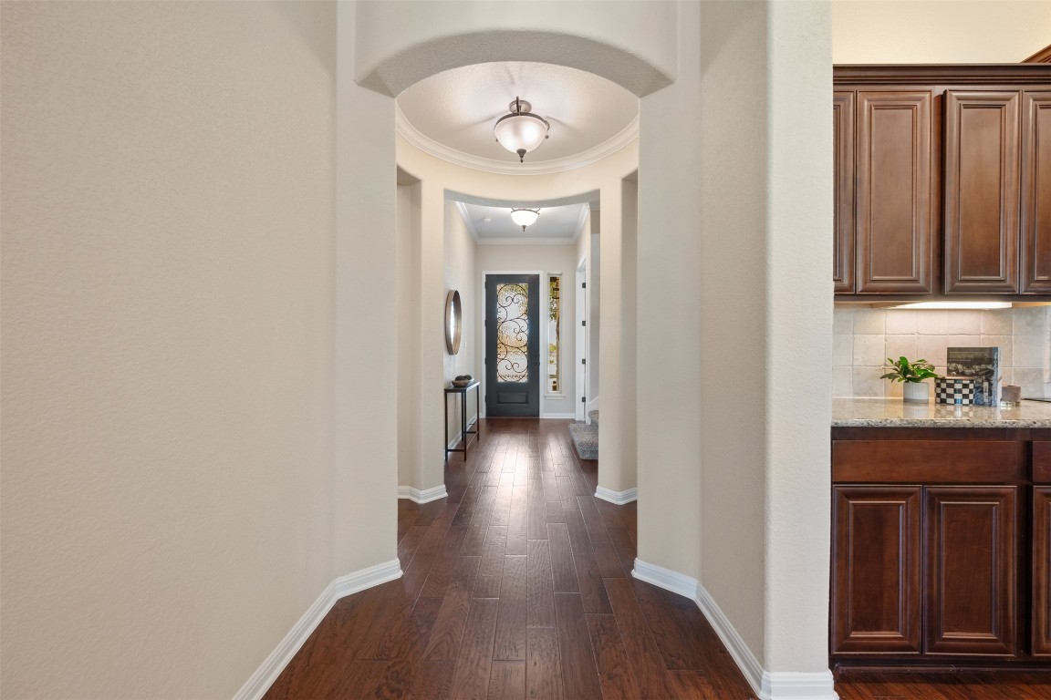 129 Camp Verde Drive Georgetown, TX 78633 - Photo 10 of 39 Corridor featuring dark wood-style floors, crown molding, and arched walkways