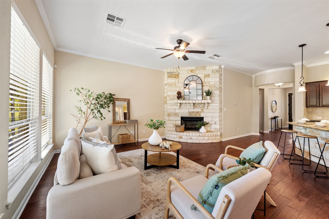 129 Camp Verde Drive Georgetown, TX 78633 - Photo 17 of 39 Living area featuring ornamental molding, dark wood finished floors, a fireplace, and ceiling fan
