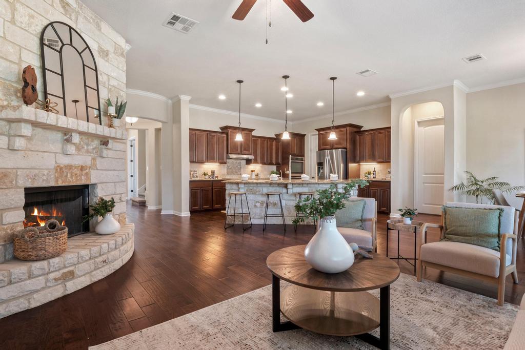 129 Camp Verde Drive Georgetown, TX 78633 - Photo 20 of 39 Living room with crown molding, arched walkways, a ceiling fan, dark wood finished floors, and a fireplace