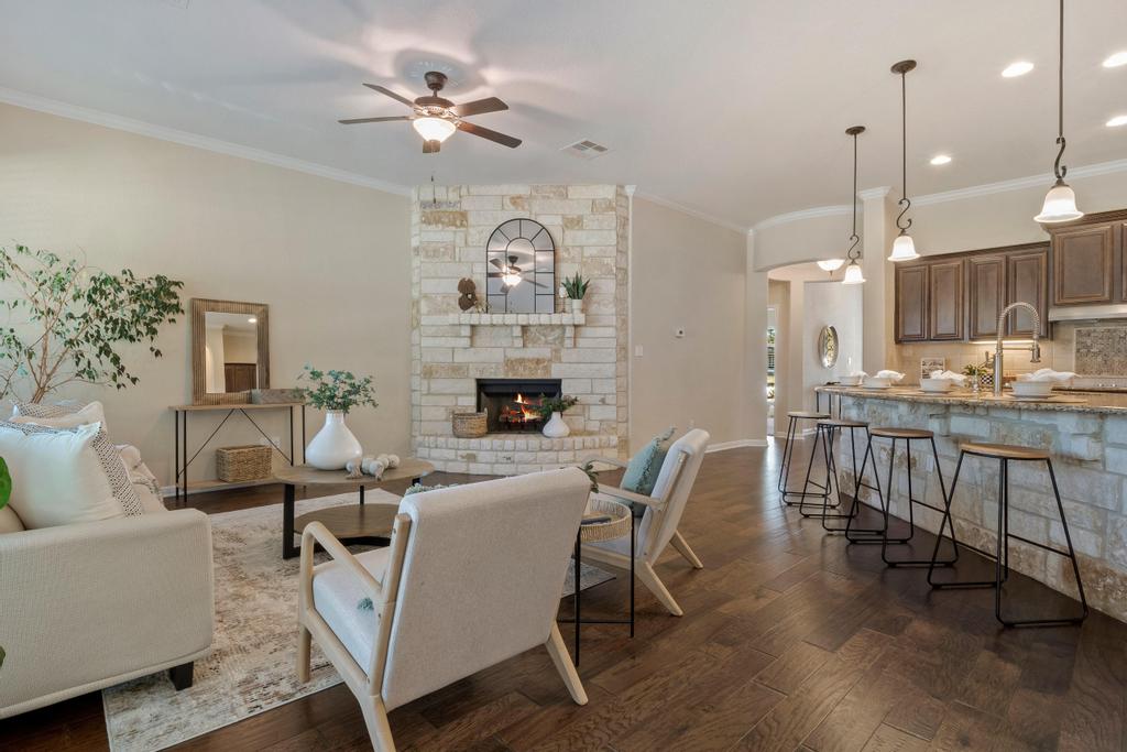 129 Camp Verde Drive Georgetown, TX 78633 - Photo 21 of 39 Living room with a fireplace, crown molding, ceiling fan, dark wood-type flooring, and arched walkways