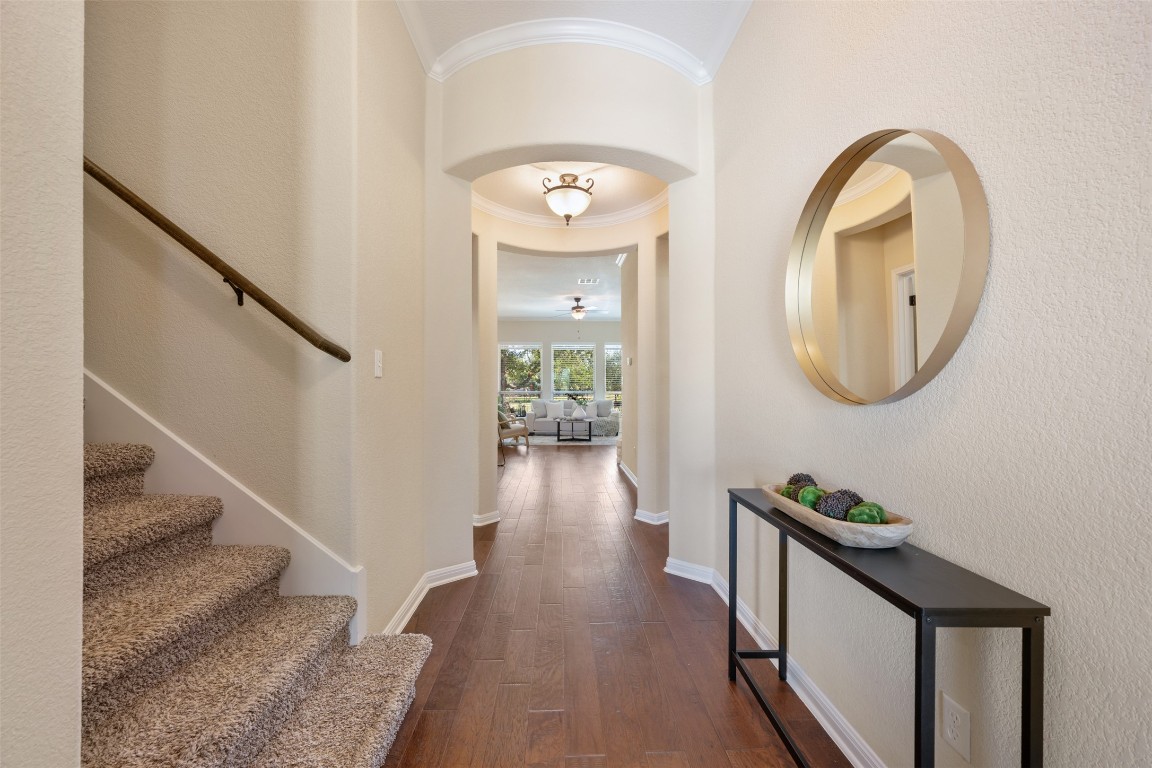 129 Camp Verde Drive Georgetown, TX 78633 - Photo 9 of 39 Hallway with dark wood finished floors, crown molding, stairs, a high ceiling, and a textured wall
