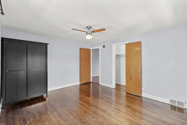 an empty room with wooden floor a ceiling fan and a window