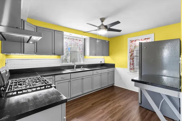 a kitchen with stainless steel appliances granite countertop a sink a stove and a wooden floors