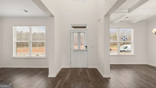 an empty room with wooden floor and windows