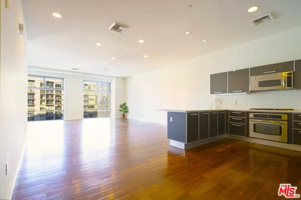 a view of kitchen with stainless steel appliances wooden floor and large window