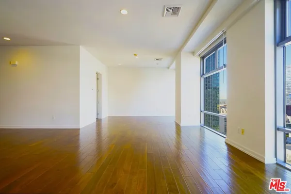 a view of a big room with wooden floor and windows