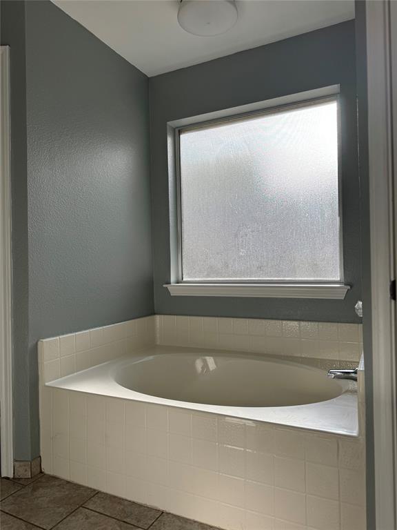 6241 Peach Tree Drive Midlothian, TX 76065 - Photo 9 of 19 Recessed soaking tub with white tile surround, frosted window, and light gray painted walls