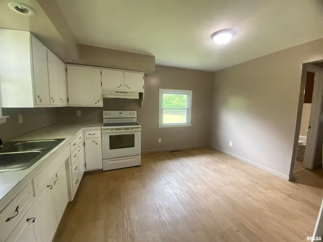 a kitchen with granite countertop a stove a sink and a refrigerator