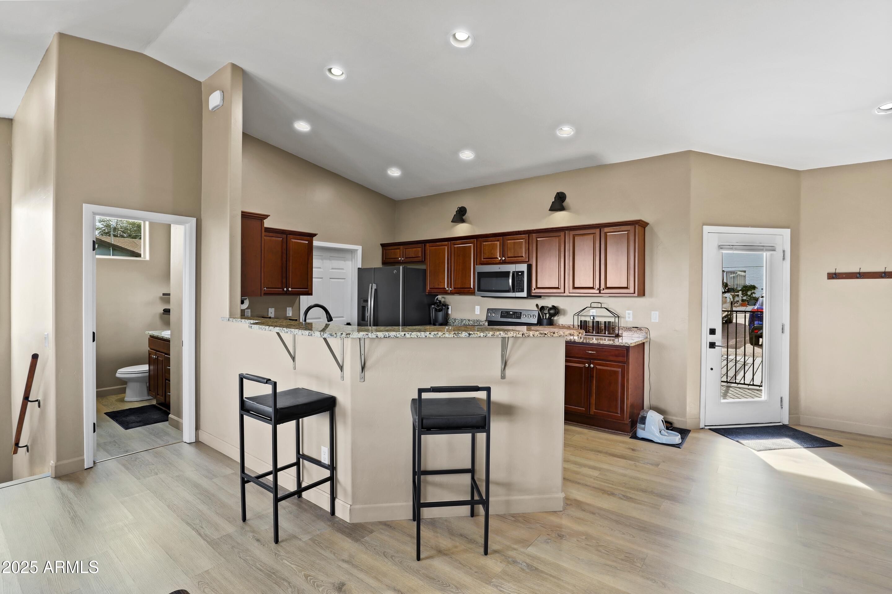 308 West Rim View Road Payson, AZ 85541 - Photo 7 of 57 a kitchen with stainless steel appliances kitchen island granite countertop a refrigerator a stove top oven a sink dishwasher and white cabinets with wooden floor