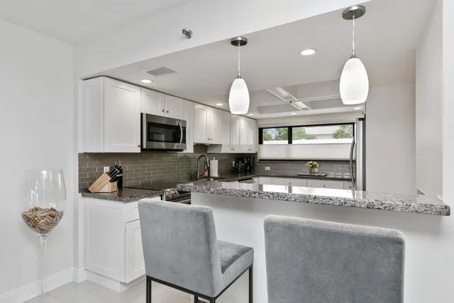 a kitchen with stainless steel appliances granite countertop a sink a stove top oven a chimney and a counter top space