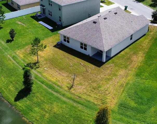 an aerial view of a house with swimming pool and large trees