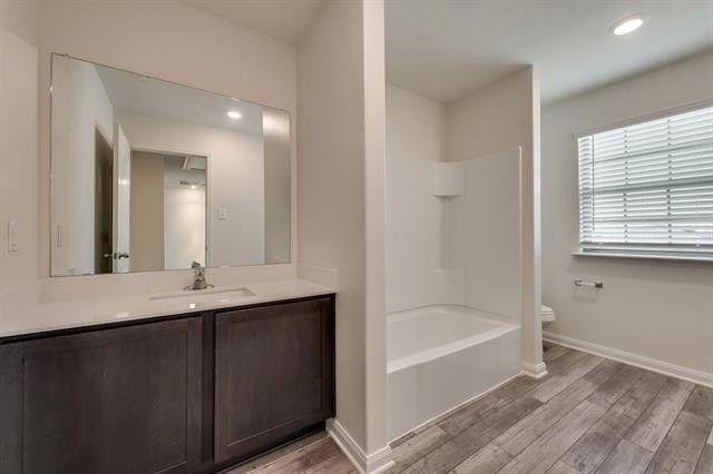 13609 Mineral Road Ponder, TX 76259 - Photo 19 of 21 Bathroom featuring a dark wood-finish vanity with a light-toned countertop, an integrated sink, a large wall-mounted mirror, and wood-finish flooring