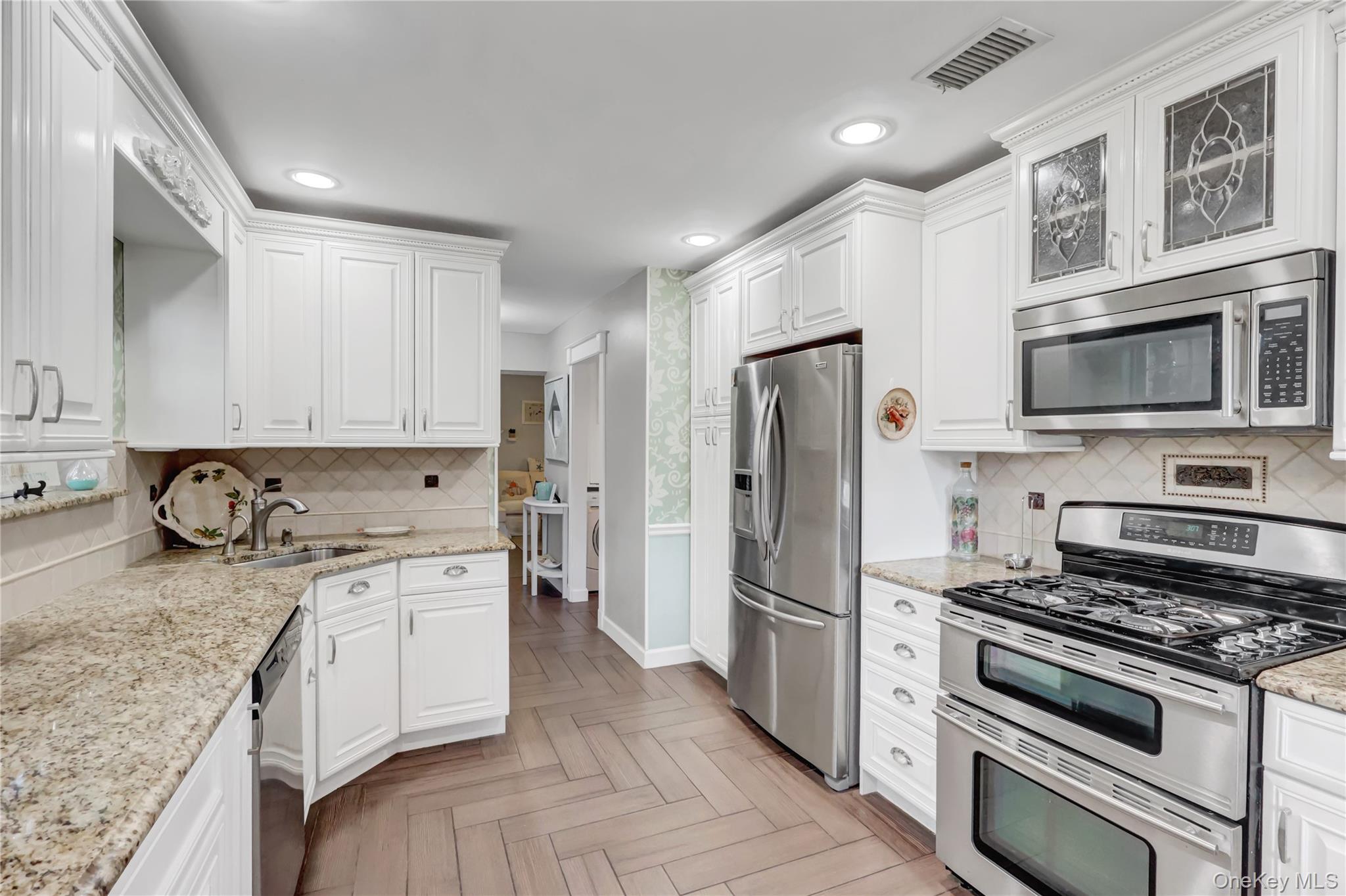 14 Chipmunk Trail Coram, NY 11727 - Photo 12 of 41 a kitchen with stainless steel appliances granite countertop a stove top oven a refrigerator and white cabinets with wooden floor
