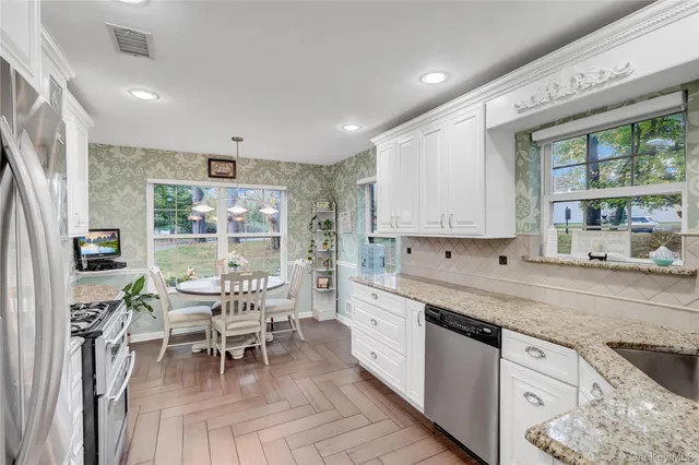 a kitchen with stainless steel appliances granite countertop a stove top oven a sink a dining table and chairs