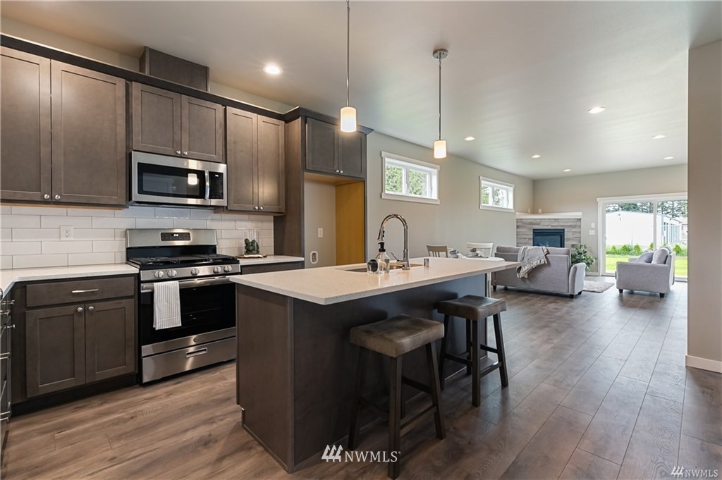 6934 Red Ridge Drive, Unit B Lynden, WA 98264 - Photo 8 of 34 a kitchen with stainless steel appliances kitchen island granite countertop a stove a sink dishwasher a microwave oven and a dining table with wooden floor