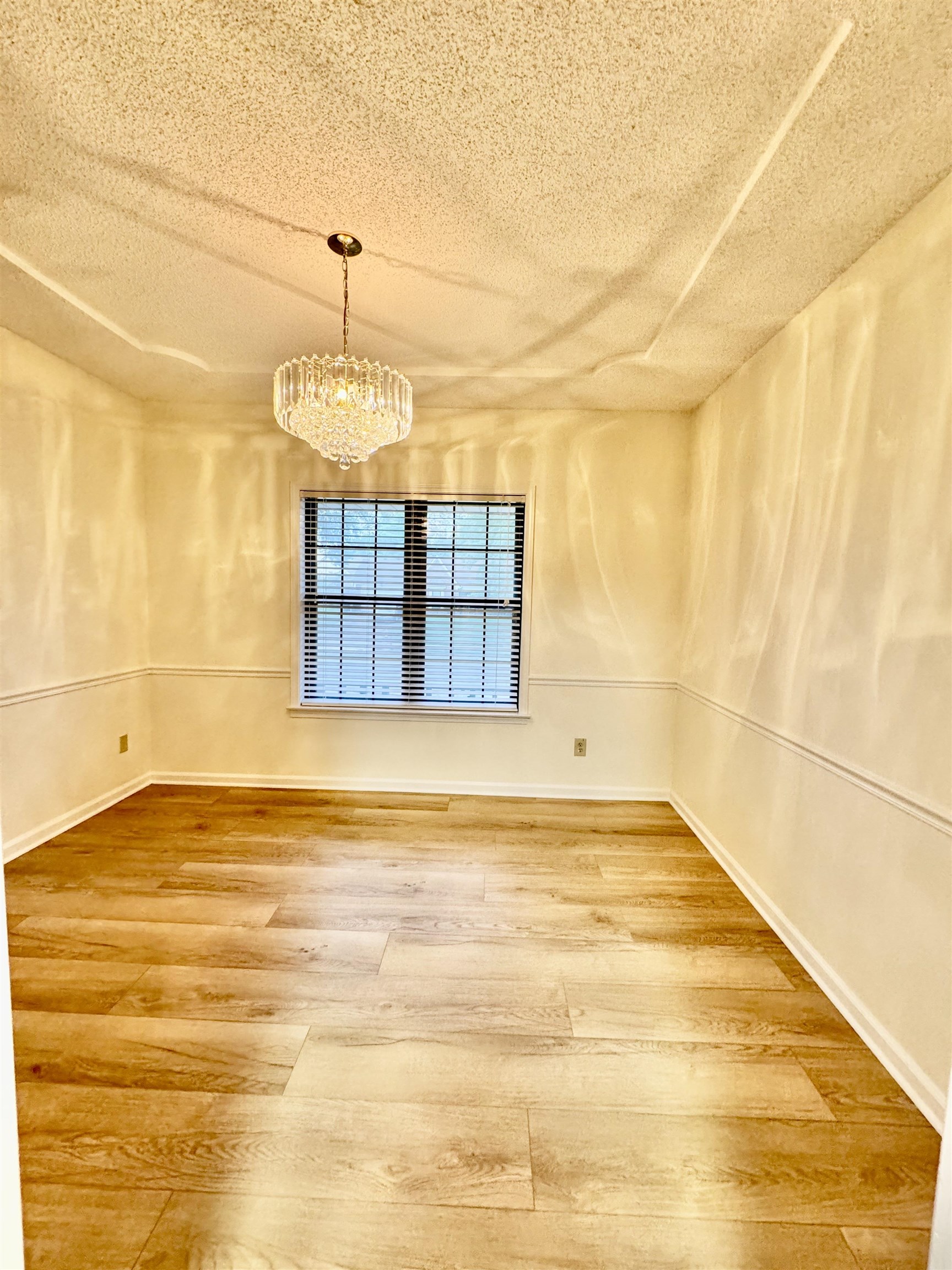 7245 Barnstable Road Memphis, TN 38125 - Photo 11 of 36 Empty room featuring a chandelier, a textured ceiling, and hardwood / wood-style floors