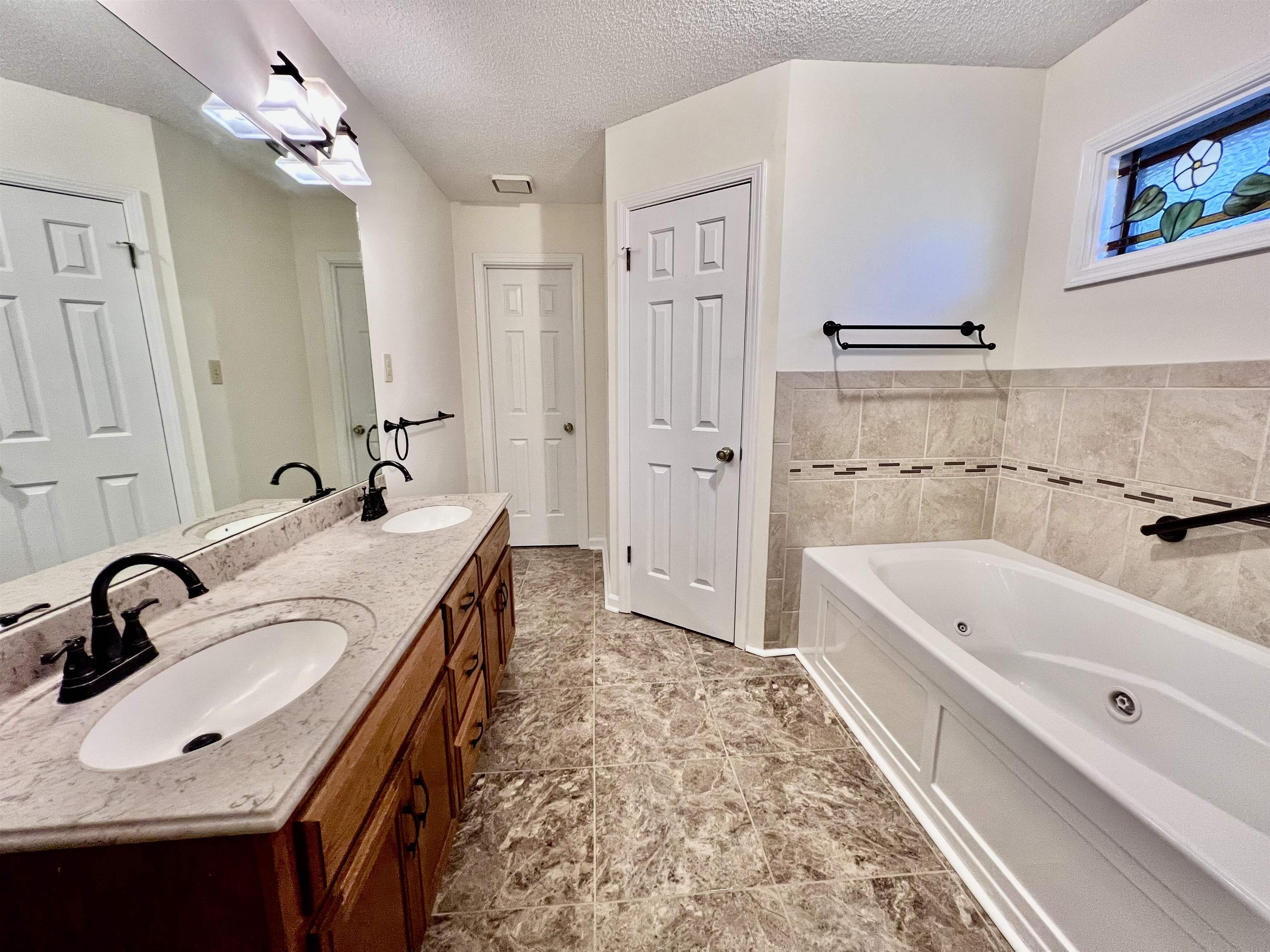 7245 Barnstable Road Memphis, TN 38125 - Photo 15 of 36 Bathroom featuring vanity, a tub to relax in, a textured ceiling, and tile walls