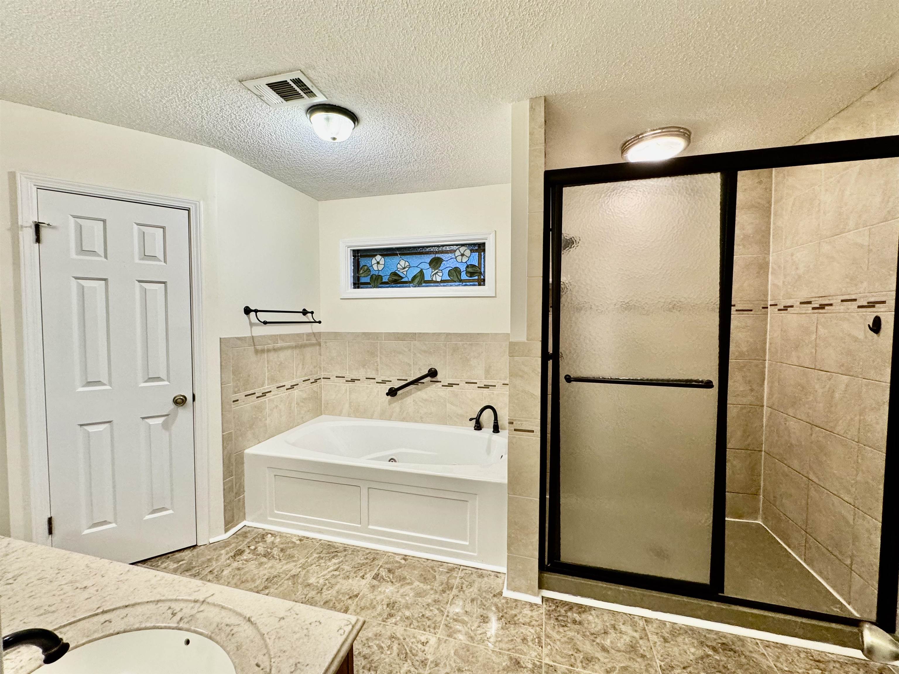 7245 Barnstable Road Memphis, TN 38125 - Photo 16 of 36 Bathroom featuring vanity, independent shower and bath, a textured ceiling, tile walls, and tile patterned flooring