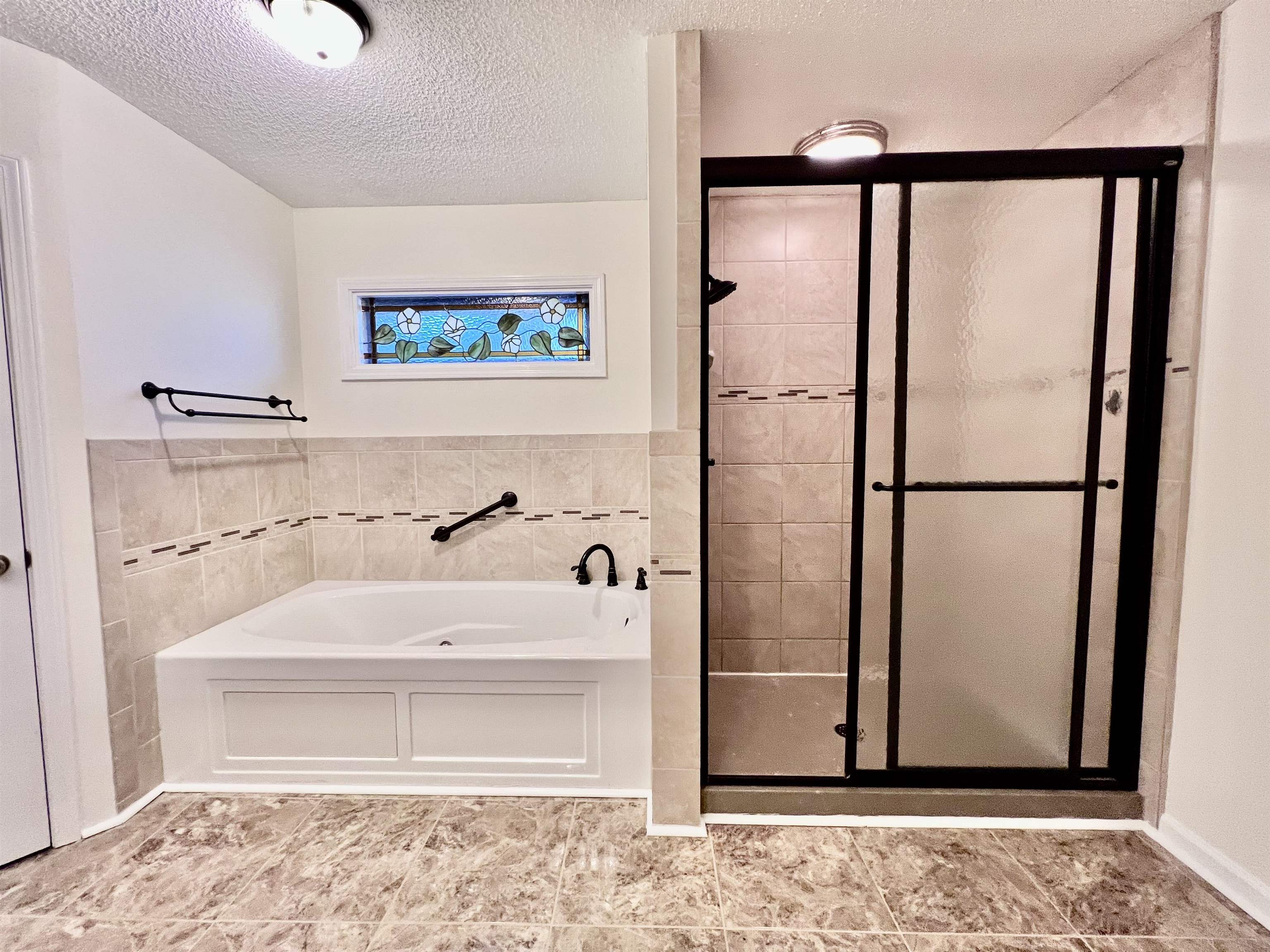 7245 Barnstable Road Memphis, TN 38125 - Photo 17 of 36 Bathroom featuring tile walls, a textured ceiling, and separate shower and tub