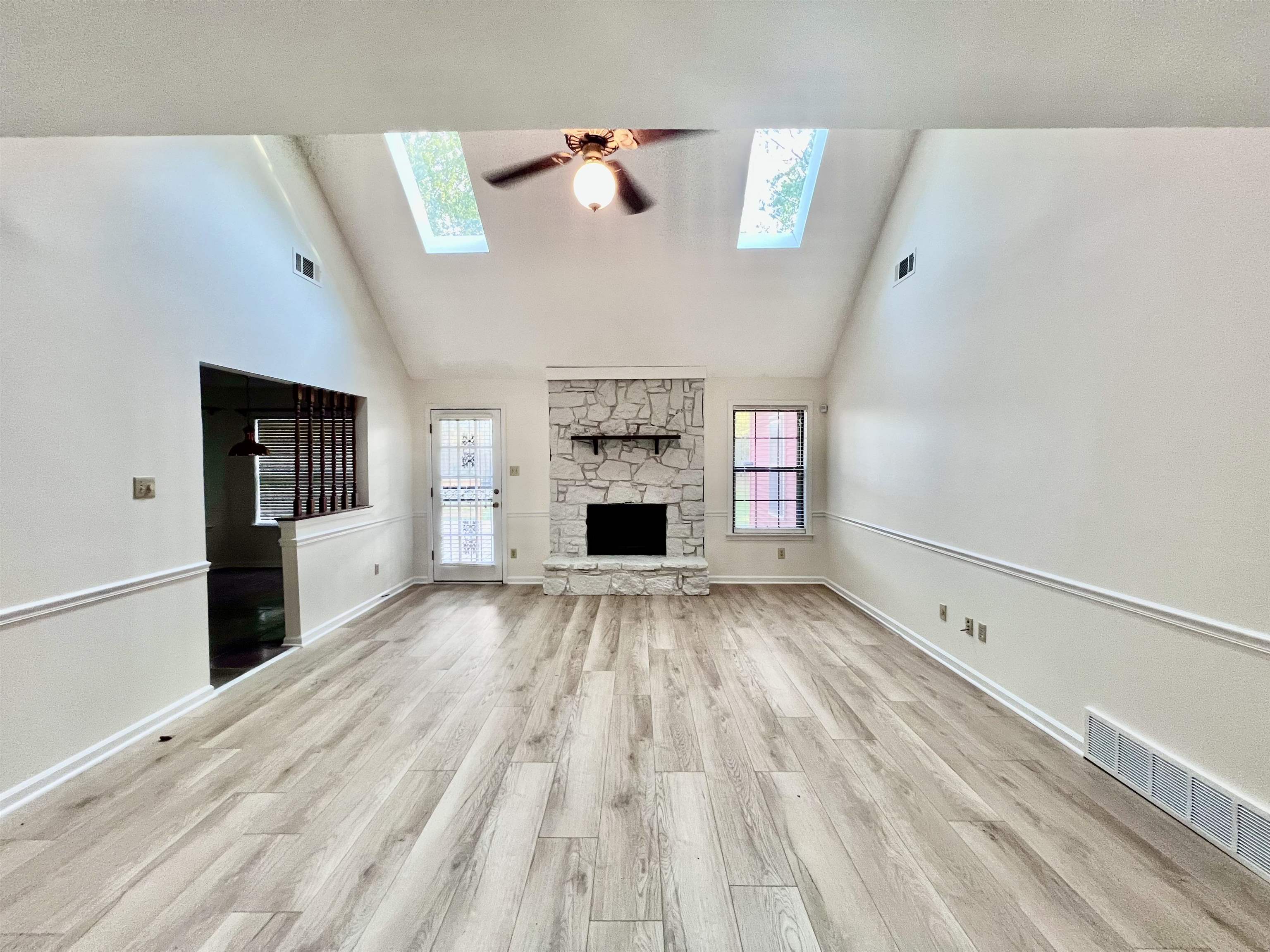 7245 Barnstable Road Memphis, TN 38125 - Photo 6 of 36 Unfurnished living room featuring light wood-type flooring, a fireplace, a skylight, and high vaulted ceiling