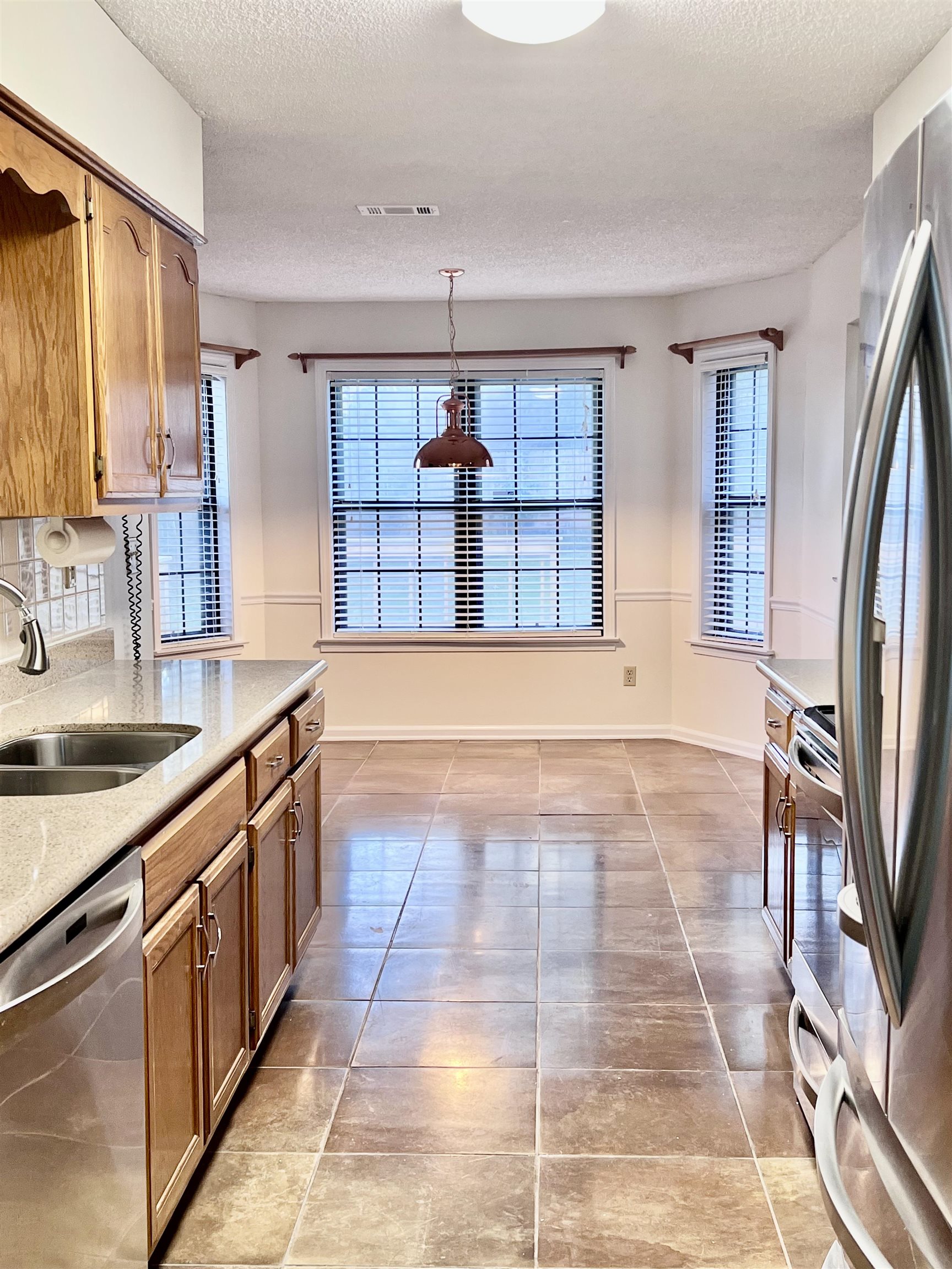 7245 Barnstable Road Memphis, TN 38125 - Photo 8 of 36 Kitchen featuring pendant lighting, a textured ceiling, light tile patterned flooring, sink, and appliances with stainless steel finishes