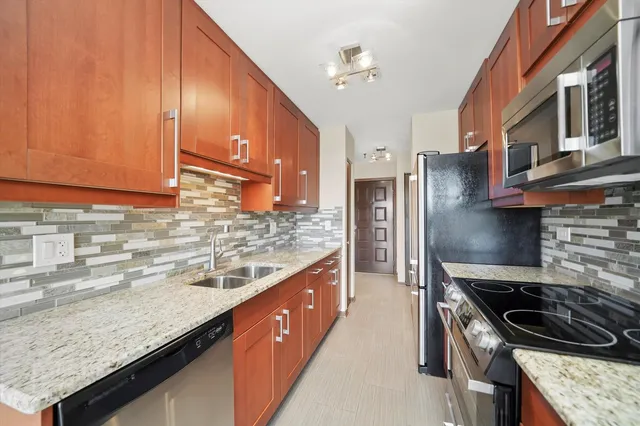 a kitchen with stainless steel appliances granite countertop a sink stove and refrigerator