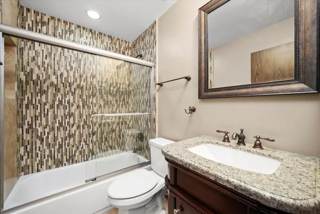 a bathroom with a granite countertop sink toilet a mirror and shower