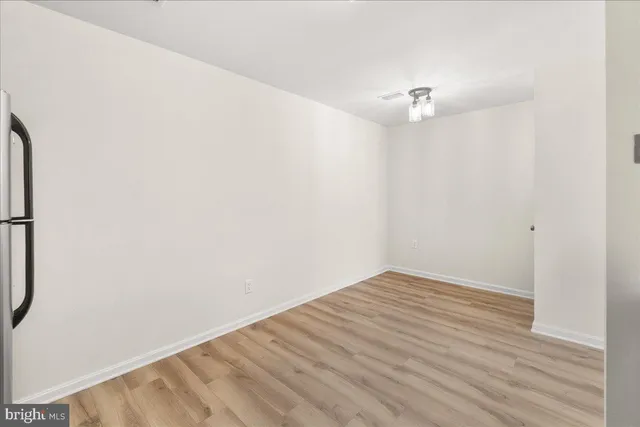 an empty room with wooden floor and a ceiling fan