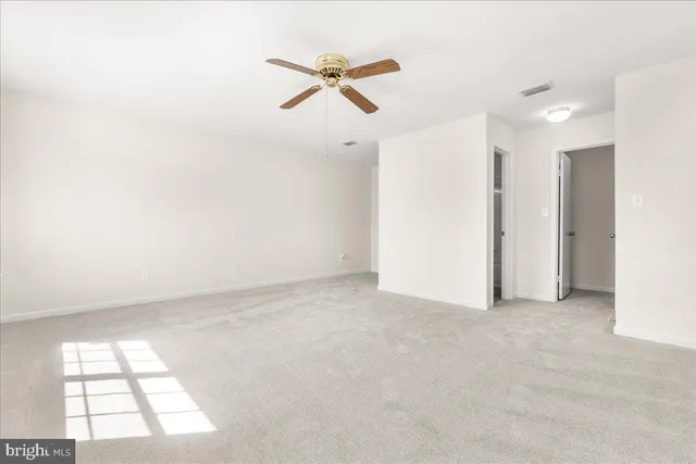 an empty room with a ceiling fan and window