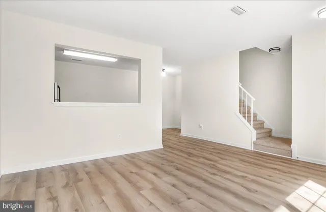 a view of an empty room with wooden floor and a mirror