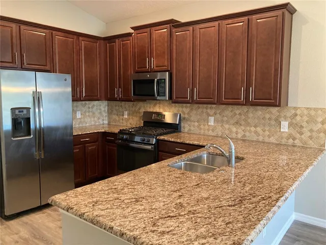 a kitchen with wooden cabinets a refrigerator and a sink