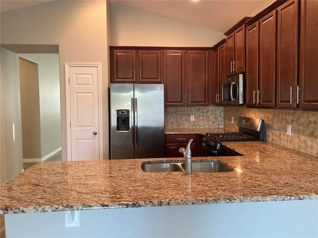 a kitchen with granite countertop a refrigerator and a sink