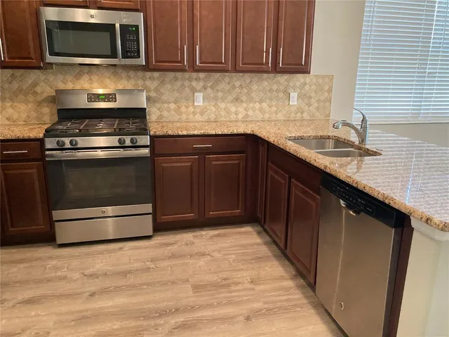 a kitchen with granite countertop wooden cabinets and stainless steel appliances