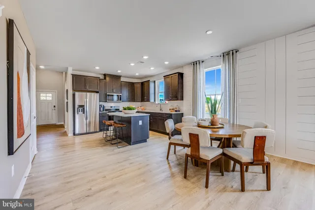 a living room with stainless steel appliances kitchen island granite countertop furniture wooden floor and a kitchen view