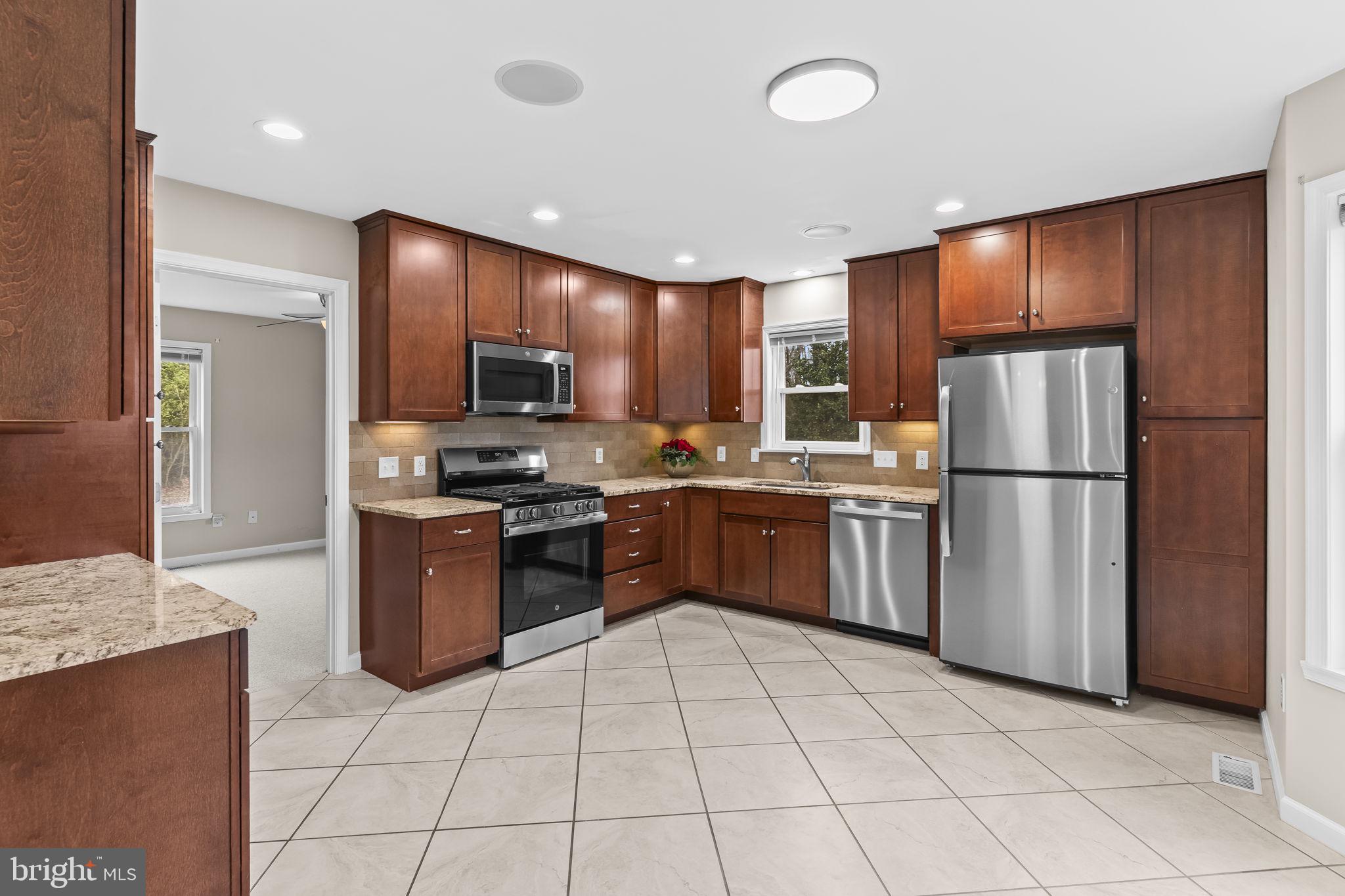 25001 Half Pone Point Road Hollywood, MD 20636 - Photo 14 of 40 a kitchen with granite countertop a refrigerator a stove top oven and cabinets