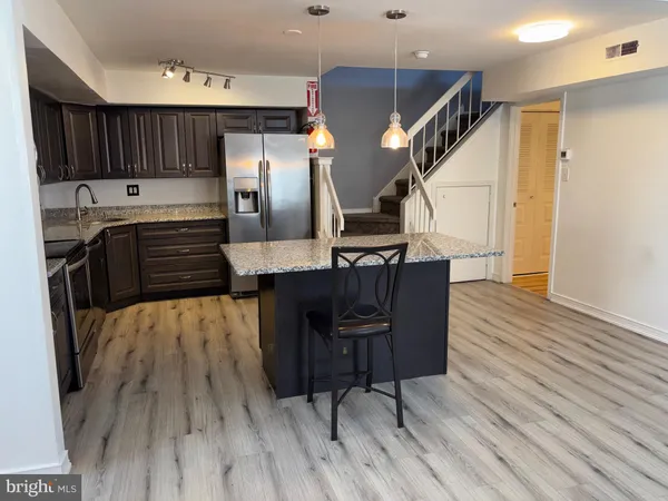 a kitchen with granite countertop wooden floors cabinets a sink and appliances