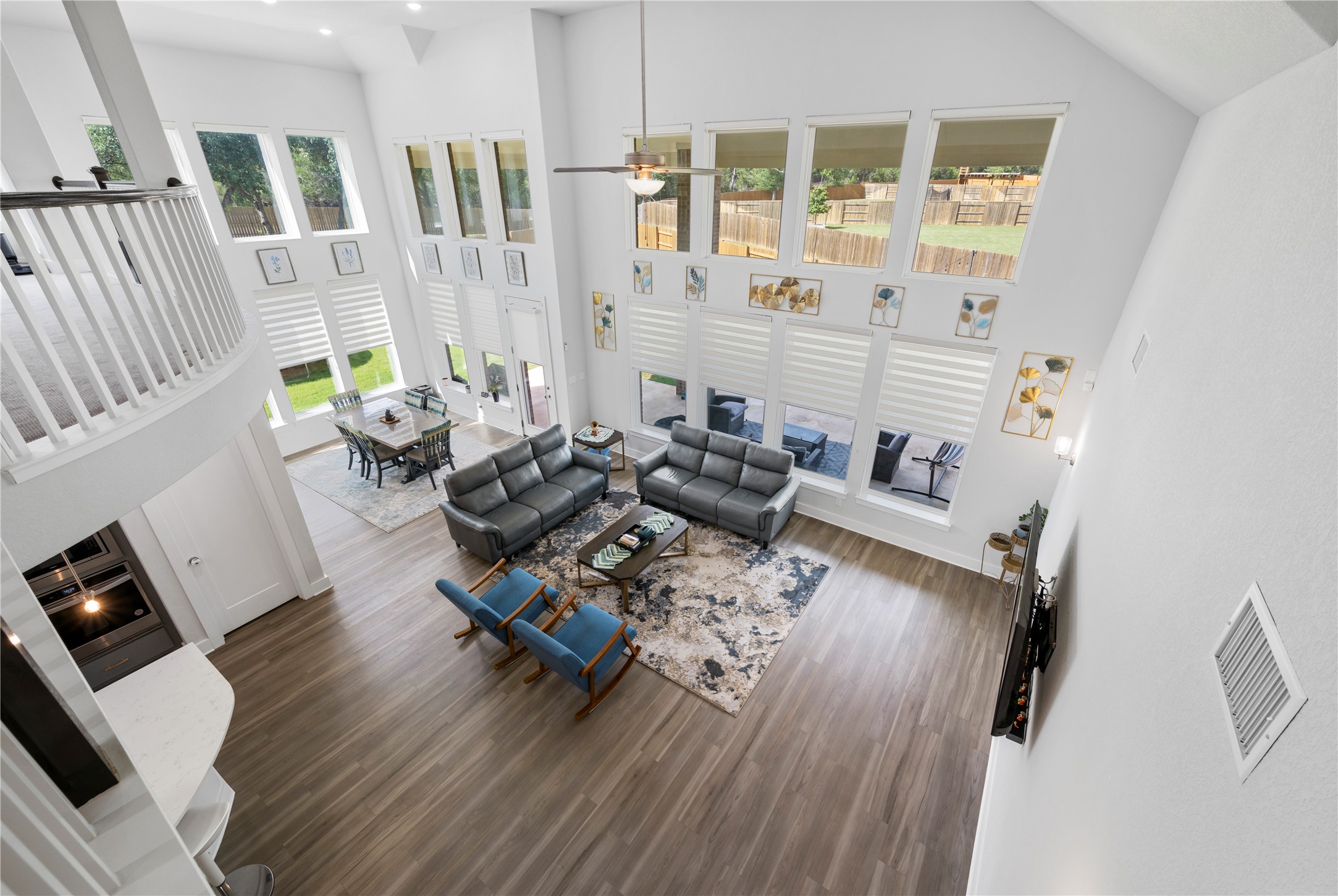 105 Autumn Oak Way Georgetown, TX 78628 - Photo 31 of 40 Vaulted ceiling living space featuring extensive window arrays, wood-finish flooring, and a second-story interior balcony with white spindle railing