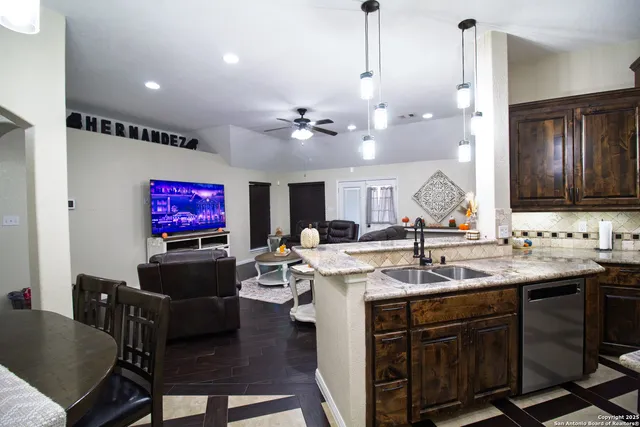a view of kitchen island a sink stainless steel appliances and living room view